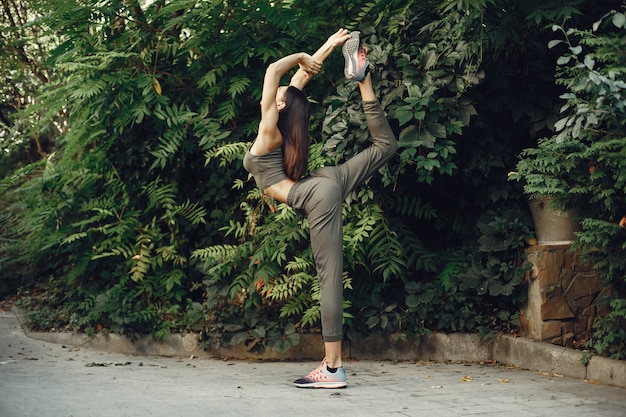 La bella ragazza di sport in un parco dell&#39;estate