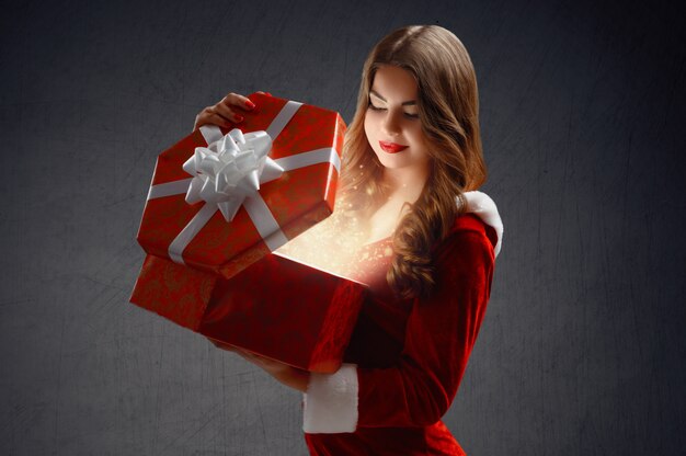 La bella ragazza in abito rosso di Snow Maiden apre un regalo per Capodanno