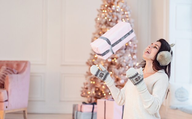 La bella ragazza in un vestito bianco solleva un regalo.