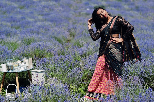 La bella ragazza indiana indossa l'abito tradizionale saree india nel campo di lavanda viola