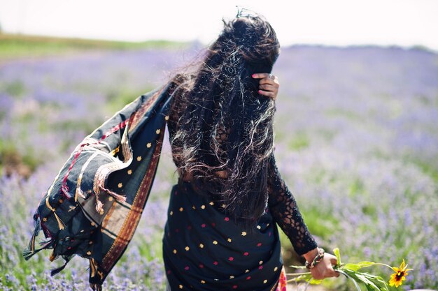 La bella ragazza indiana indossa l'abito tradizionale saree india nel campo di lavanda viola