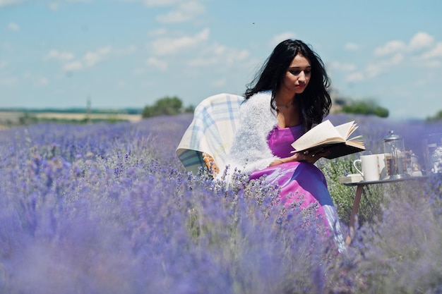 La bella ragazza indiana indossa l'abito tradizionale saree india seduto nel campo di lavanda viola con decorazioni