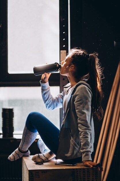 La bella ragazza stava bevendo acqua da una bottiglia di plastica, calda mattina di sole