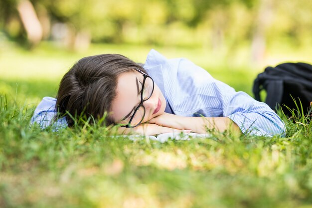 La bella ragazza teenager dorme sull'erba nella giornata di sole del parco