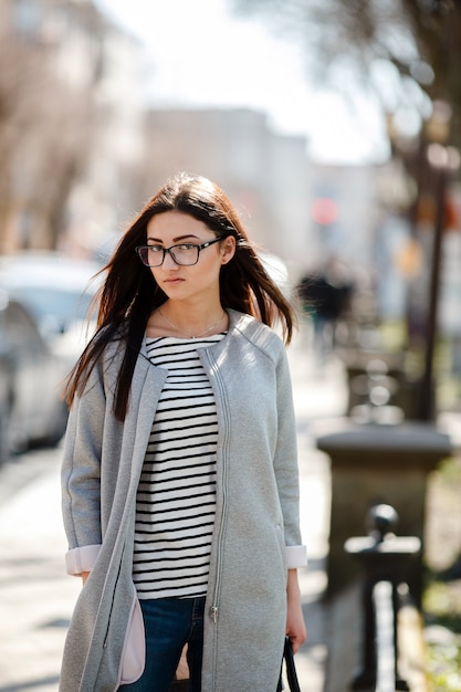 La bellissima modella che indossa un cappotto cammina nella città europea