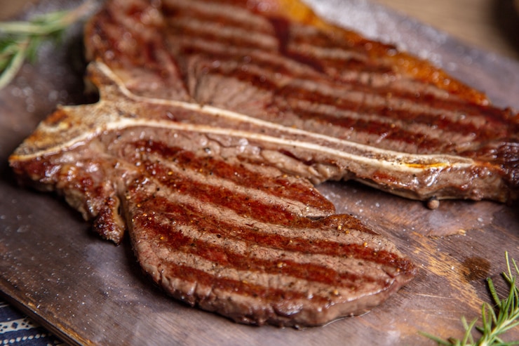 Foto gratuito la carne di vista vicina della parte anteriore sulla griglia ha fritto saporito sullo scrittorio di legno con le erbe