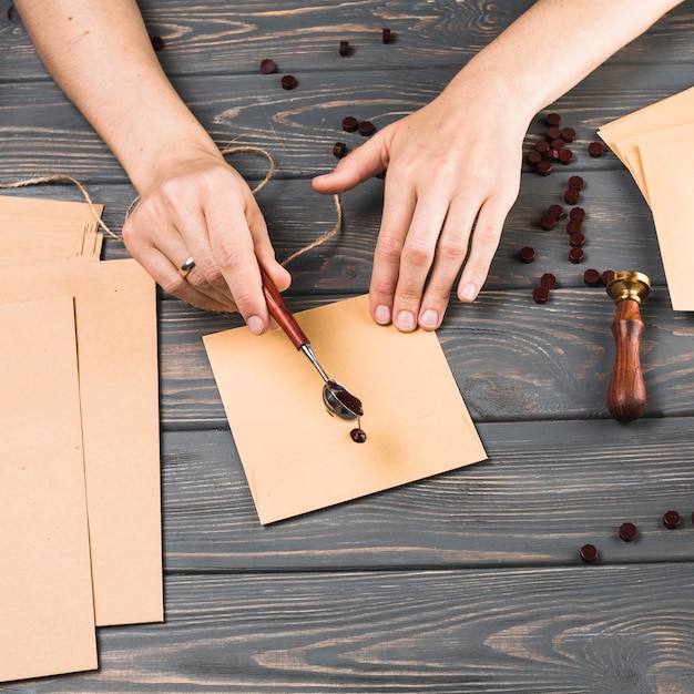 La cera di versamento della colata della mano della donna del primo piano più avvolge sul fondo di legno di struttura