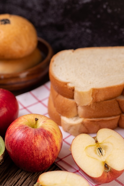 La colazione è composta da pane, mele, uva e kiwi su un tavolo di legno