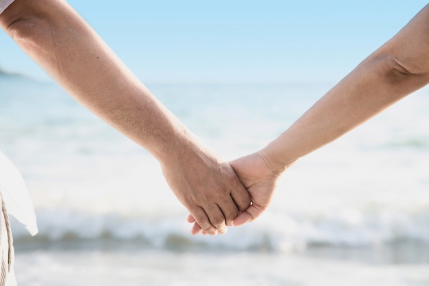 La coppia asiatica sta tenendo la mano vicino al mare