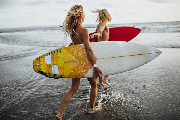 La coppia corre lungo la costa al mare. L'uomo e la donna faranno surf