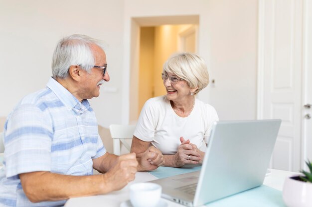 La coppia senior sta parlando online tramite connessione video sul laptop Divertirsi con amici e familiari tramite videochiamata