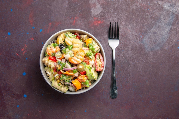 La deliziosa insalata di verdure vista dall'alto è composta da pomodori, olive e peperoni su sfondo scuro dieta per insalata di snack salutari