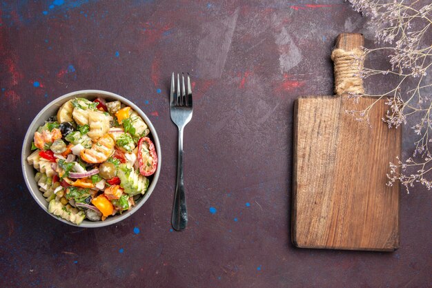 La deliziosa insalata di verdure vista dall'alto è composta da pomodori, olive e peperoni su uno sfondo scuro dieta di insalata salutare