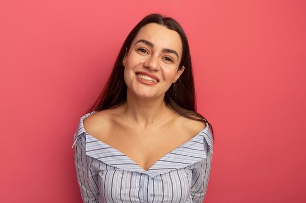 La donna abbastanza caucasica sorridente esamina la macchina fotografica sul colore rosa