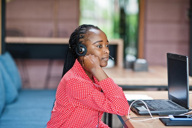 La donna afroamericana lavora in un operatore di call center e un agente del servizio clienti che indossa cuffie con microfono che lavorano su laptop