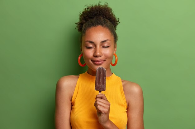 La donna afroamericana positiva brividi con gelato freddo isolato