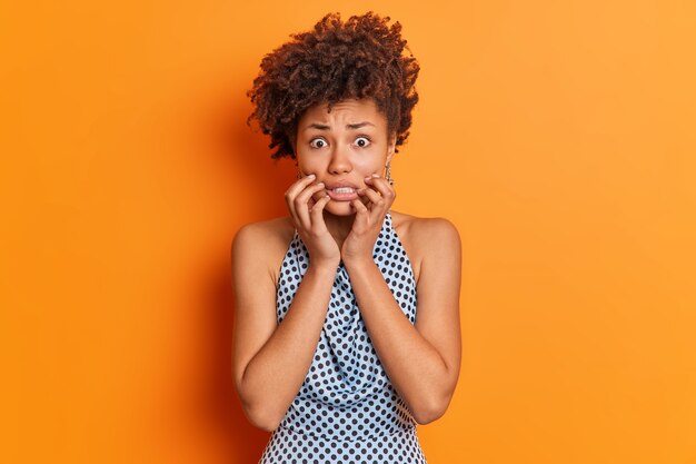 La donna afroamericana preoccupata nervosa stringe i denti sembra imbarazzata alla macchina fotografica