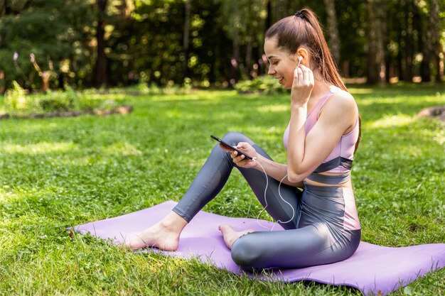 La donna atletica in abiti sportivi sta guardando sullo schermo del cellulare