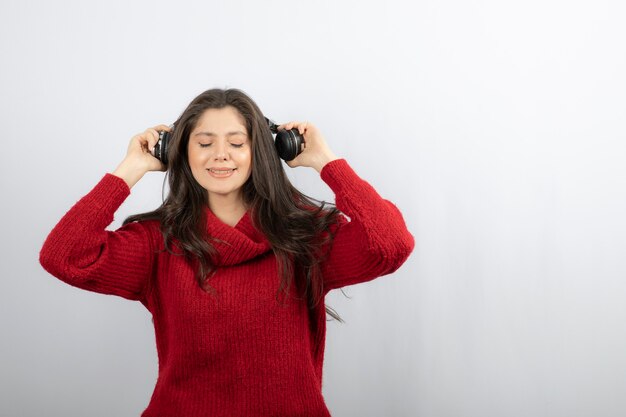 La donna attraente con gli occhi chiusi tiene le mani sull'auricolare.