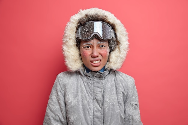 La donna avventurosa insoddisfatta rabbrividisce dal freddo trascorre molto tempo durante la forte tempesta di neve va snowboard indossa giacca invernale.