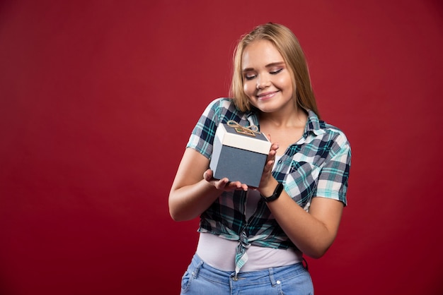 La donna bionda diventa più felice e sorpresa quando riceve una confezione regalo.