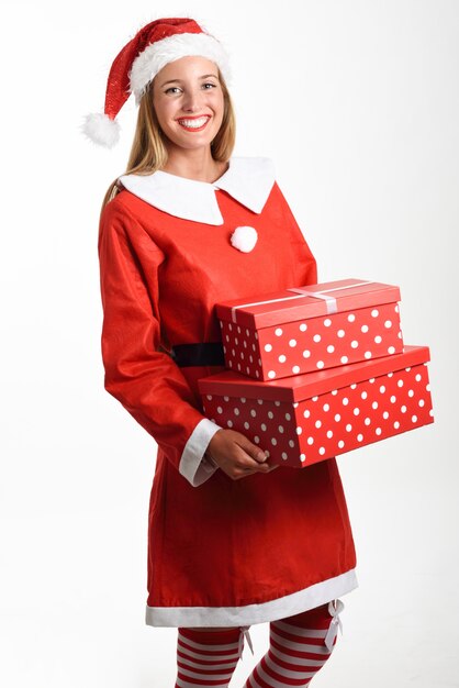 La donna bionda in vestiti di Santa Claus che sorride con i contenitori di regalo.