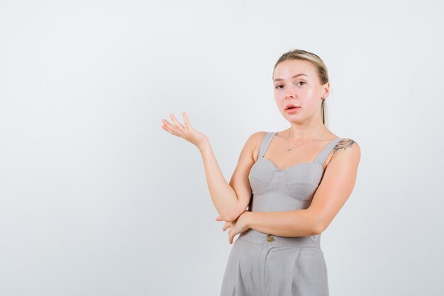 La donna bionda punta a sinistra con la mano su sfondo bianco