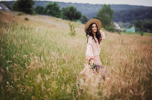 La donna cammina con il mazzo di lavanda attraverso il campo verde