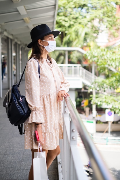 La donna caucasica che cammina sul passaggio della metropolitana in maschera medica mentre la pandemia nella città di Bangkok.