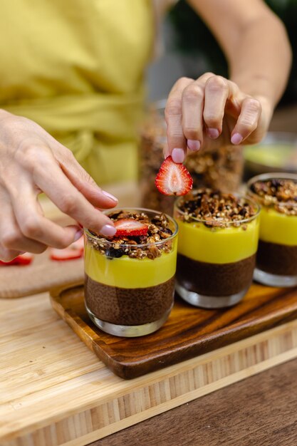 La donna caucasica in cucina fa budini di chia con marmellata di mango. Deserto a base di latte di mandorle, semi di chia, cacao, marmellata di mango e muesli.