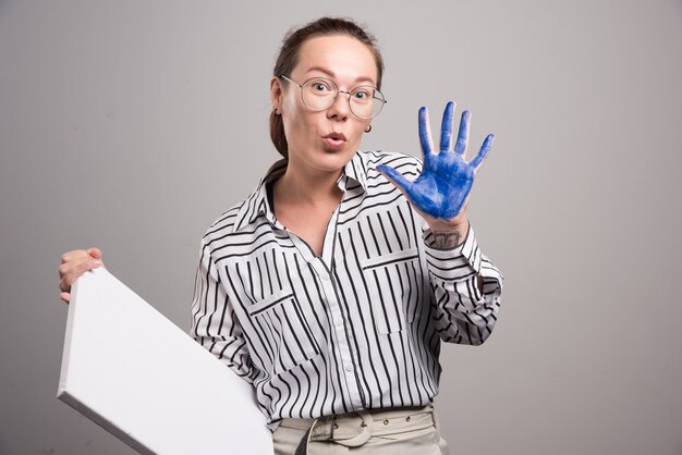 La donna che mostra la sua mano di vernice su sfondo grigio