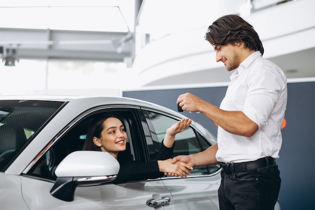 La donna che parla con il maschio seleziona la persona in una sala d'esposizione dell'automobile