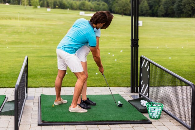 La donna che pratica il golf si muove con l'istruttore