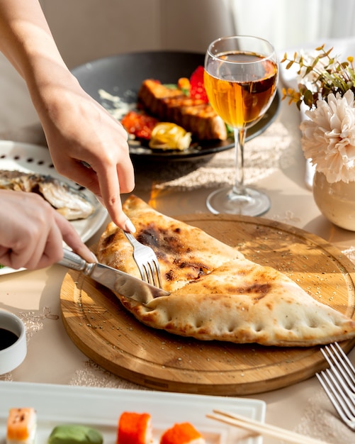 La donna che taglia la torta farcita è servito sul bordo di legno