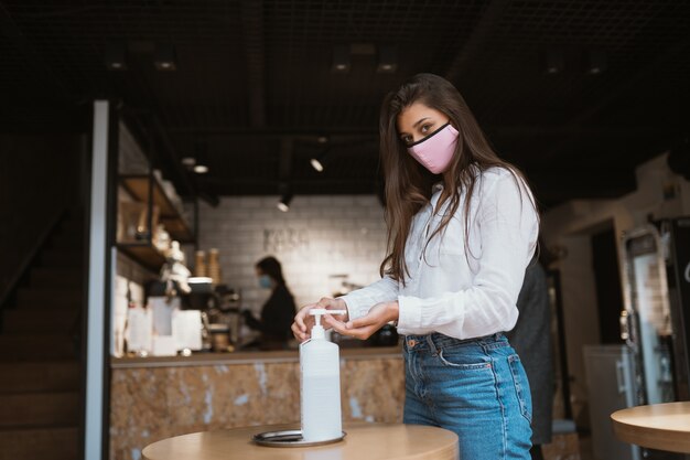 La donna che utilizza il gel disinfettante pulisce le mani dal virus del coronavirus al bar.