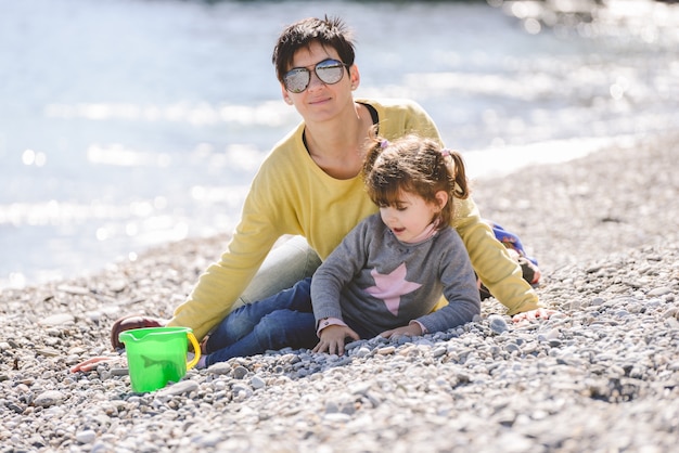 La donna con gli occhiali da sole a giocare con la figlia sulla spiaggia