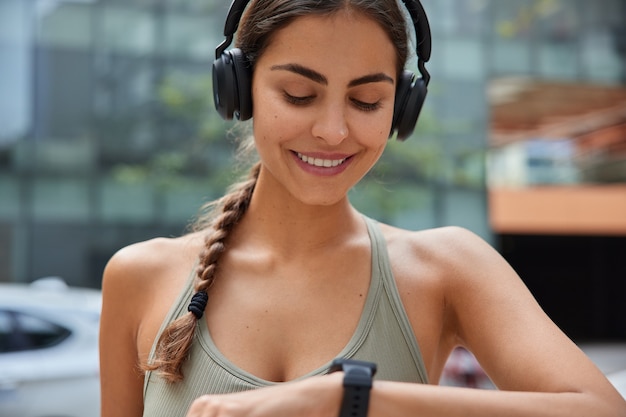 la donna con il codino controlla la frequenza cardiaca sullo smartwatch ascolta la musica nelle cuffie sta fuori