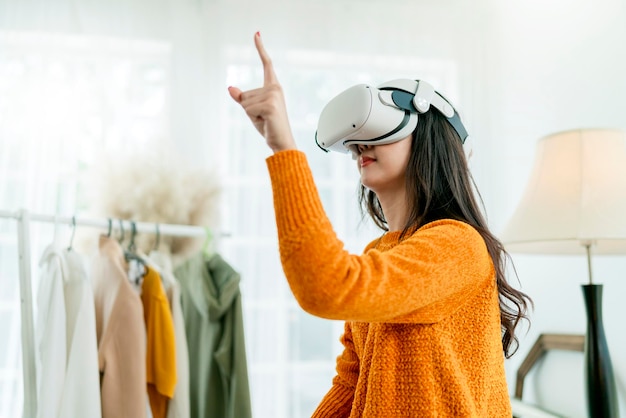 La donna d'affari asiatica intelligente partecipa alla presentazione della riunione virtuale online nuove collezioni di moda di stoffa impostate per il suo cliente in tutto il mondo utilizzando la tecnologia di realtà virtuale auricolare vr a casa studio diurno