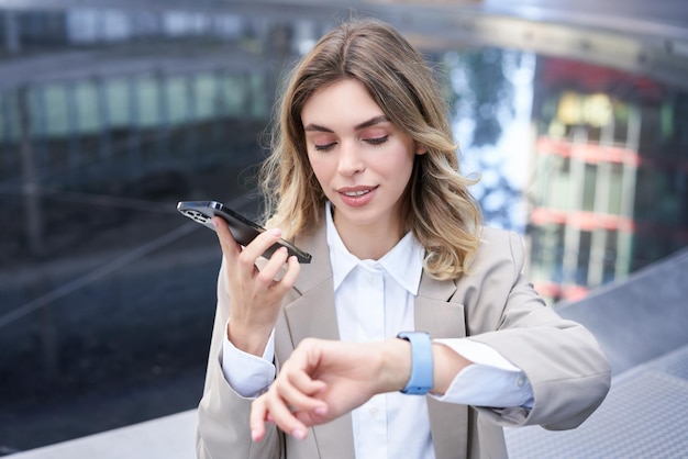 La donna d'affari controlla l'ora sull'orologio digitale e registra il messaggio vocale e organizza una riunione all'esterno