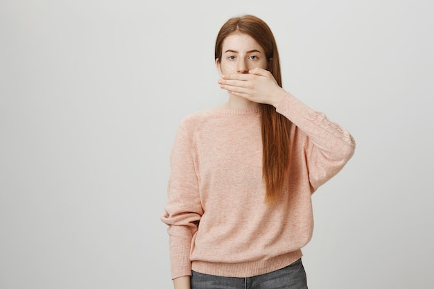 La donna dai capelli rossi seria ha chiuso la bocca con il palmo, resta in silenzio