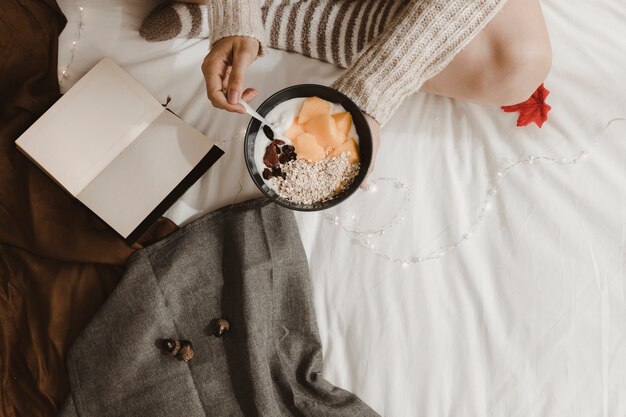 La donna del raccolto che mangia prima colazione vicino al libro