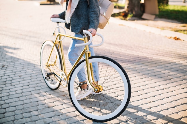 La donna del raccolto vicino alla bicicletta in parco