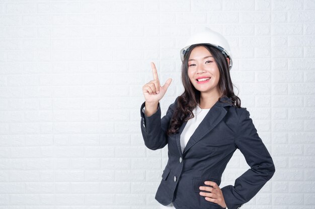 La donna dell&#39;ingegneria che tiene un cappello, separa i gesti fatti del muro di mattoni bianco con la lingua dei segni.