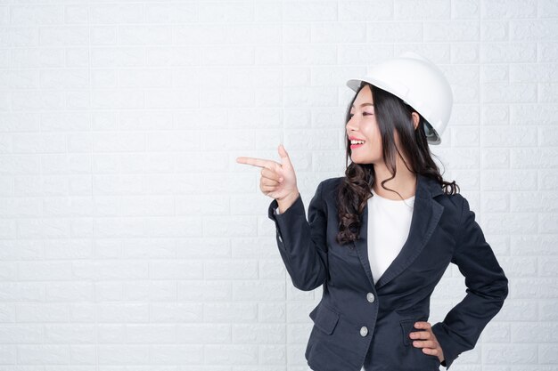 La donna dell&#39;ingegneria che tiene un cappello, separa i gesti fatti del muro di mattoni bianco con la lingua dei segni.