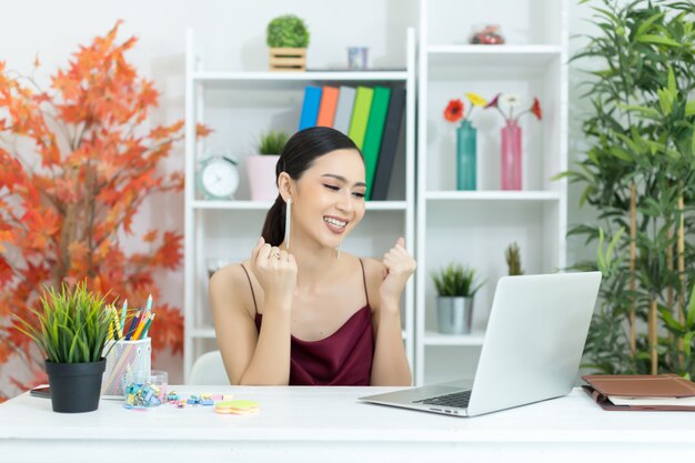 La donna di affari asiatica prende una pausa caffè dopo il lavoro al computer portatile sullo scrittorio