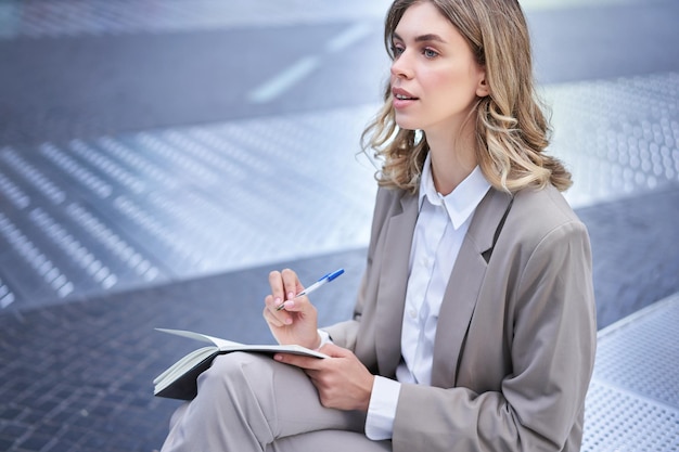 La donna di affari che scrive i suoi pensieri La signora corporativa si siede all'aperto lavora al brainstorming