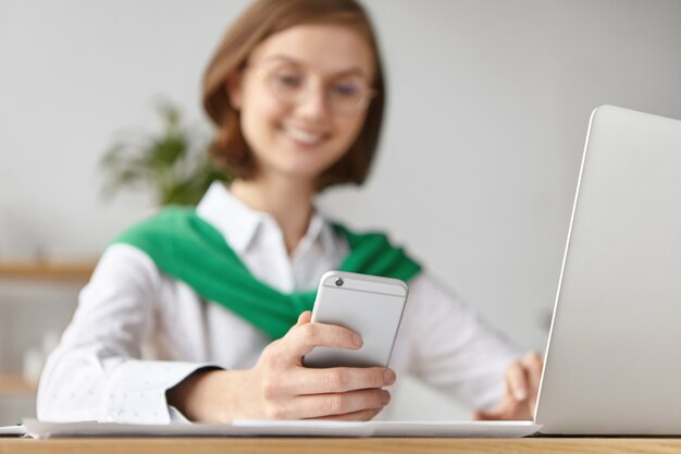 La donna di affari elegante si è vestita formalmente che si siede con il computer portatile