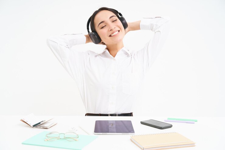 Foto gratuito la donna di affari sorridente in cuffie si siede alla scrivania dell'ufficio ascolta la musica e rilassa riposa dopo il lavoro w