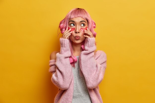 La donna di bellezza tocca le toppe, sembra meravigliata sopra, ha un'espressione sorpresa, indossa i bigodini, vestita casualmente