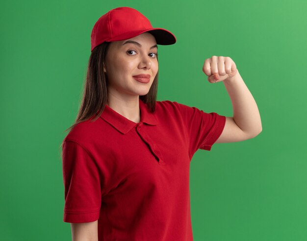 La donna di consegna graziosa sicura in uniforme tiene il pugno